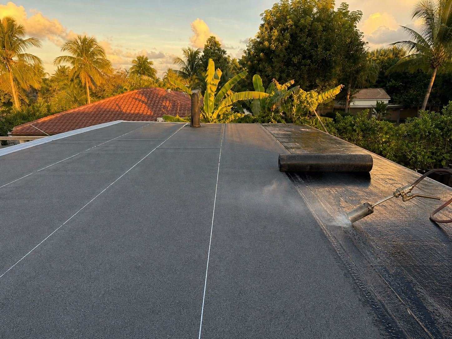 Modified bitumen roofing being installed across a low-slope roof section